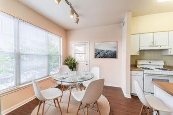 a dining room with a glass table and chairs and a kitchen with white appliances